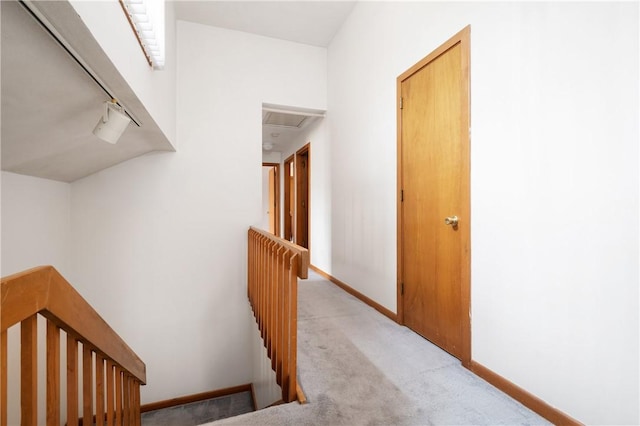hallway with baseboards, light colored carpet, attic access, and an upstairs landing