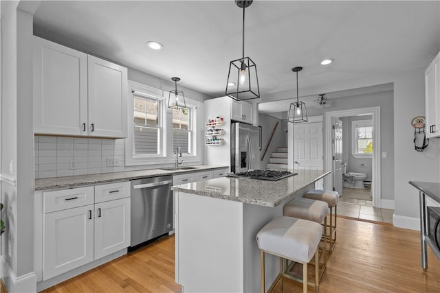 kitchen featuring a sink, white cabinets, a breakfast bar area, and stainless steel appliances