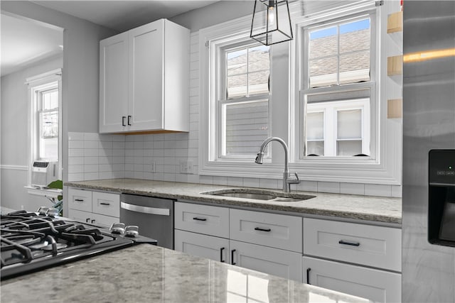 kitchen with a sink, decorative backsplash, stainless steel appliances, and white cabinetry