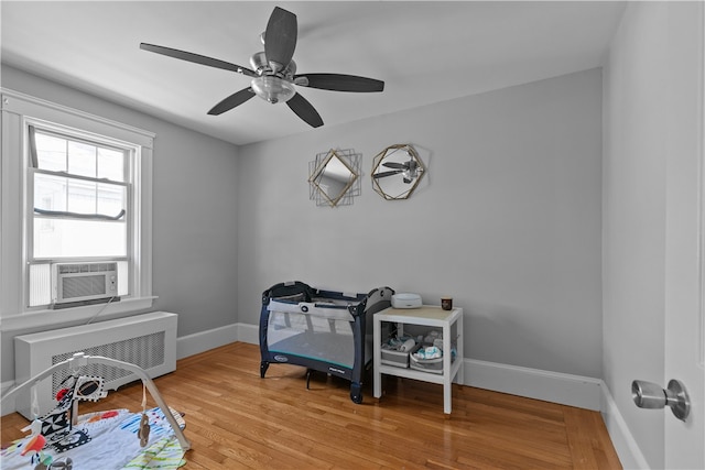 interior space featuring baseboards, cooling unit, a ceiling fan, and wood finished floors