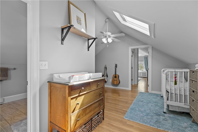 bedroom featuring baseboards, lofted ceiling with skylight, and light wood-type flooring