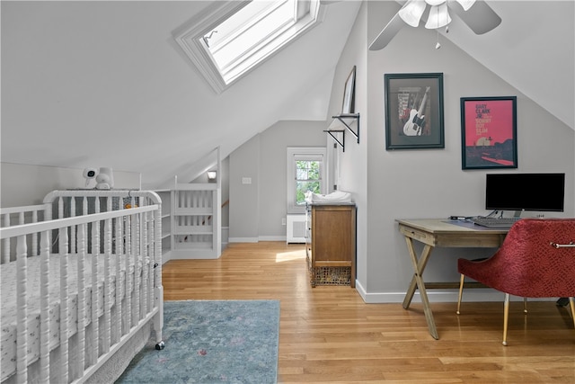 bedroom with vaulted ceiling with skylight, baseboards, a ceiling fan, and wood finished floors
