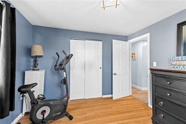 workout room featuring baseboards and light wood-style flooring