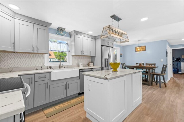 kitchen featuring light wood-style floors, a barn door, tasteful backsplash, a sink, and stainless steel appliances