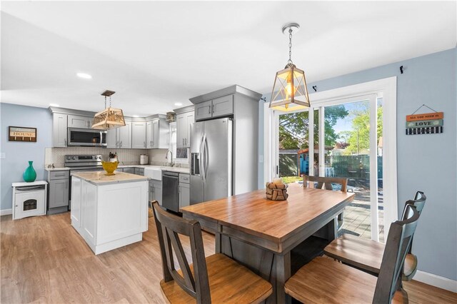 kitchen with light wood-style floors, stainless steel appliances, tasteful backsplash, a kitchen island, and gray cabinetry