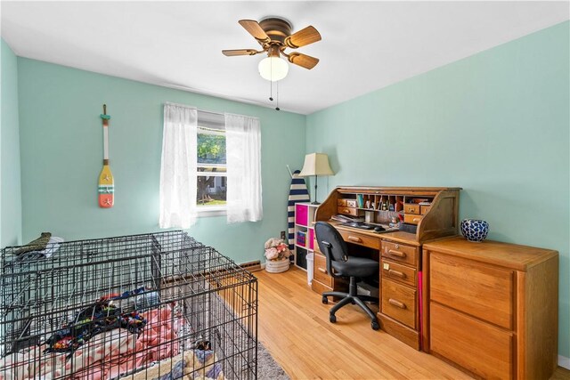 office with light wood-style floors, a ceiling fan, and baseboards