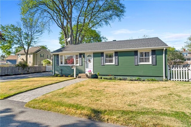 single story home featuring a shingled roof, fence, and a front yard