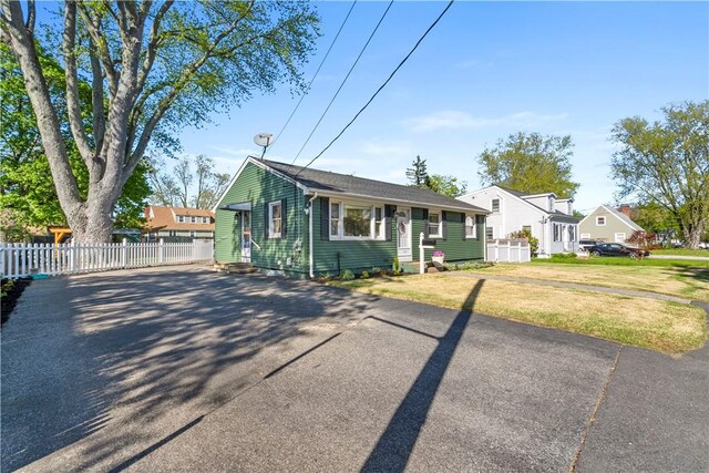 bungalow-style house featuring entry steps, fence, a front lawn, and aphalt driveway