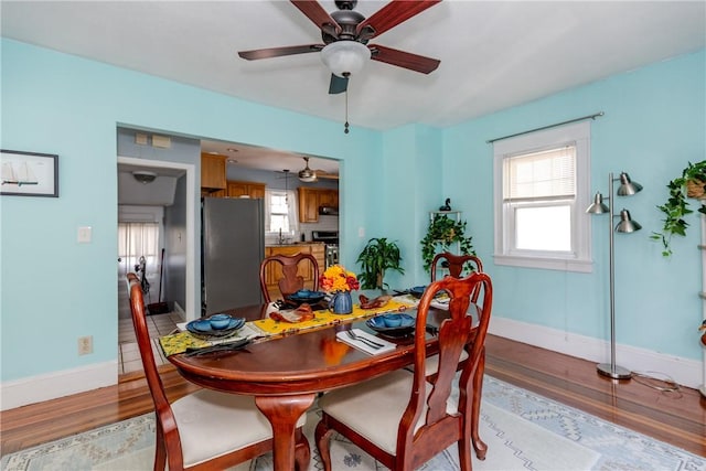 dining area featuring light wood-style floors, baseboards, and ceiling fan