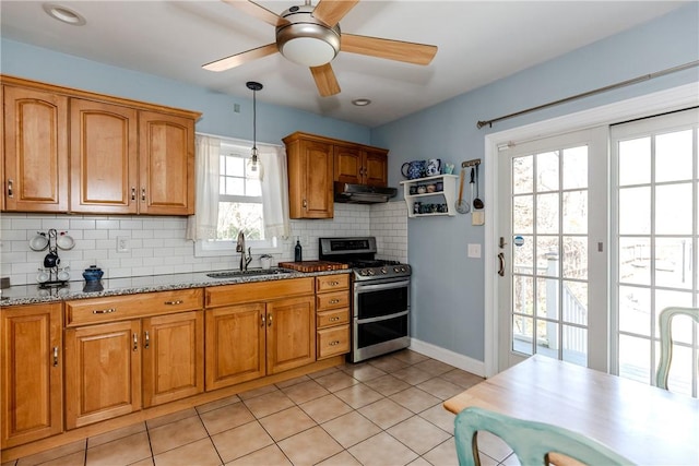 kitchen with a sink, brown cabinetry, range with two ovens, tasteful backsplash, and under cabinet range hood