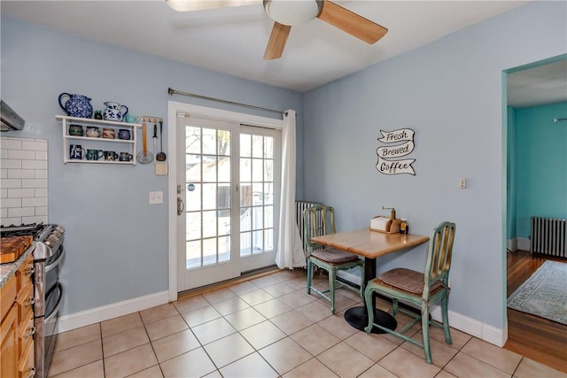 dining room featuring radiator heating unit, baseboards, light tile patterned floors, and a ceiling fan