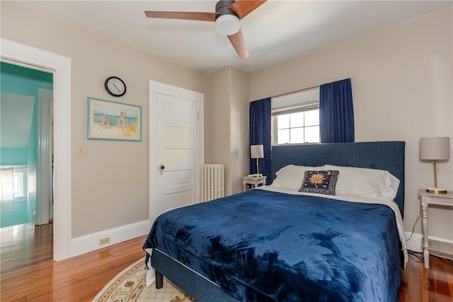 bedroom with baseboards, radiator, ceiling fan, and wood finished floors