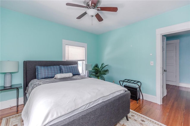bedroom with a ceiling fan, baseboards, and wood finished floors