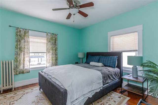bedroom featuring baseboards, ceiling fan, wood finished floors, and radiator