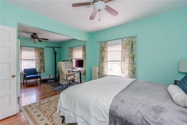 bedroom featuring ceiling fan, radiator, and light wood-style floors