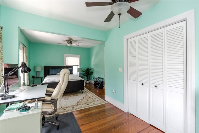 bedroom featuring baseboards, a ceiling fan, a closet, and wood finished floors