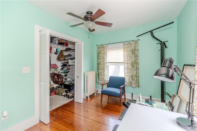 office with a ceiling fan, baseboards, radiator heating unit, and light wood-style flooring