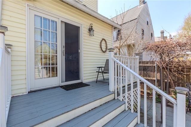 property entrance featuring fence, a chimney, and a deck