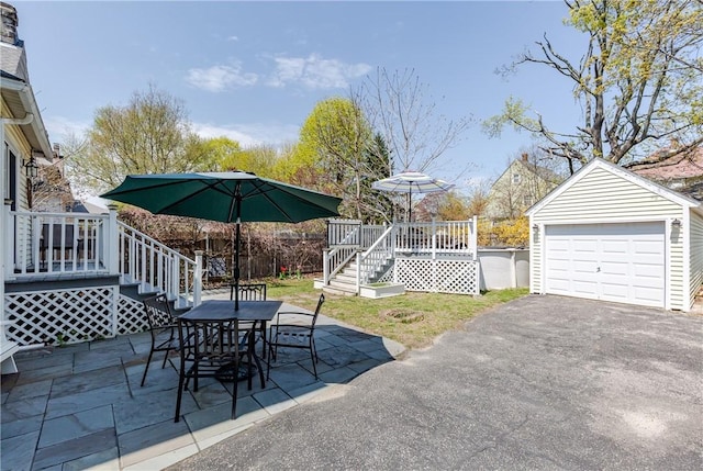 view of patio with driveway, an outbuilding, a wooden deck, stairway, and a detached garage