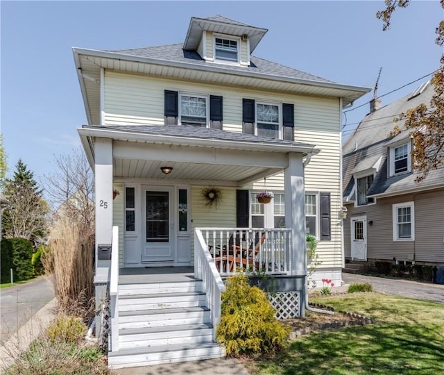 american foursquare style home with covered porch and a shingled roof