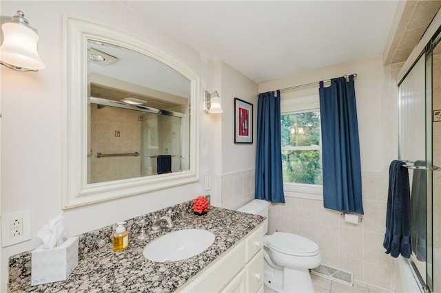 bathroom featuring visible vents, tile walls, a shower stall, vanity, and toilet
