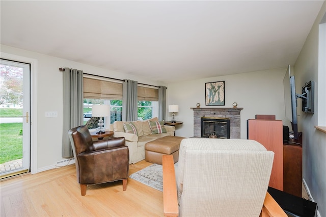 living room with light wood-type flooring, a baseboard radiator, and a fireplace