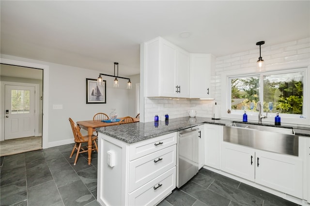 kitchen featuring stainless steel dishwasher, a peninsula, white cabinetry, backsplash, and hanging light fixtures