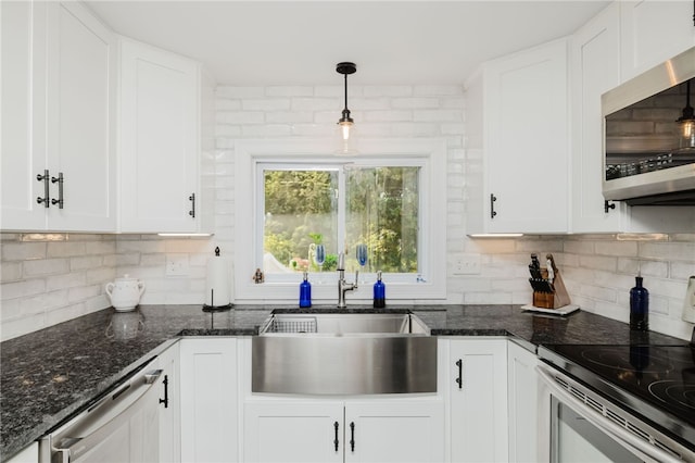 kitchen with white cabinets, a sink, backsplash, decorative light fixtures, and stainless steel appliances