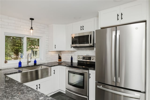 kitchen with a sink, dark stone counters, appliances with stainless steel finishes, and white cabinetry