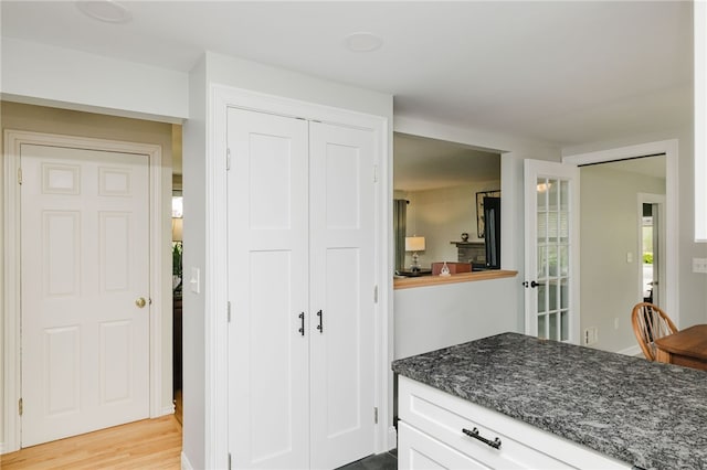 kitchen with dark stone countertops, light wood finished floors, and white cabinetry