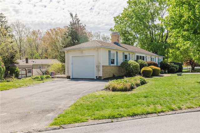 view of front of property with brick siding, a garage, a front yard, a chimney, and driveway
