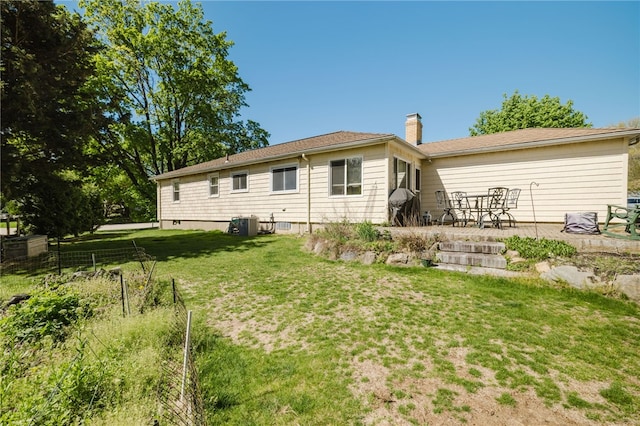 back of house featuring a yard, a patio, fence, and a chimney