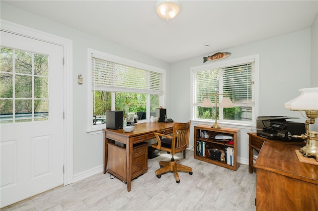 office space featuring baseboards, plenty of natural light, and light wood finished floors
