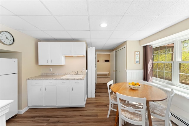 29 Howard Ave, Scituate, RI 02831 - kitchen with baseboard heating, a sink, freestanding refrigerator, white cabinetry, and dark wood-type flooring