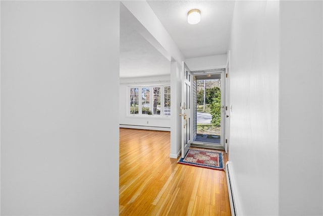doorway with baseboards, a baseboard radiator, baseboard heating, and wood finished floors