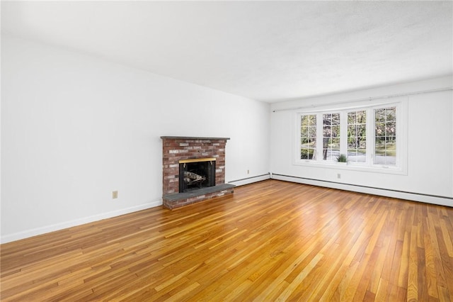 unfurnished living room with baseboards, a baseboard heating unit, light wood-style flooring, and a fireplace