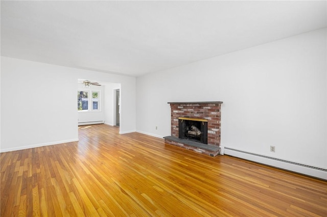 unfurnished living room with baseboards, light wood-style flooring, a brick fireplace, and baseboard heating