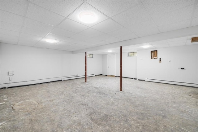 finished basement with a baseboard radiator, a paneled ceiling, and baseboard heating