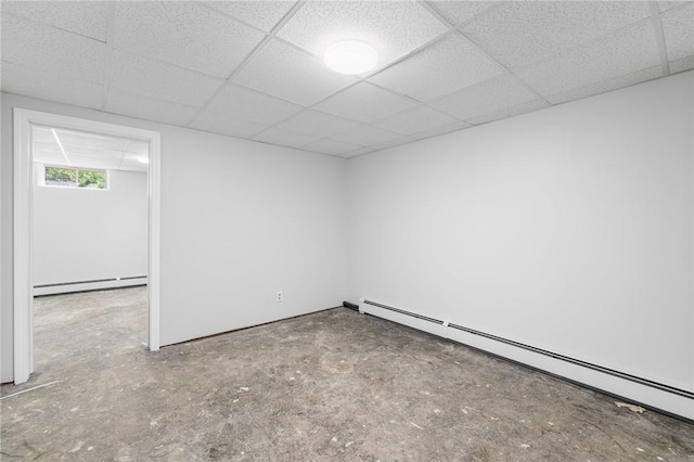 empty room featuring concrete flooring, a drop ceiling, and baseboard heating