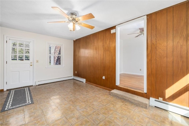 foyer with wood walls, baseboards, baseboard heating, a baseboard heating unit, and a ceiling fan