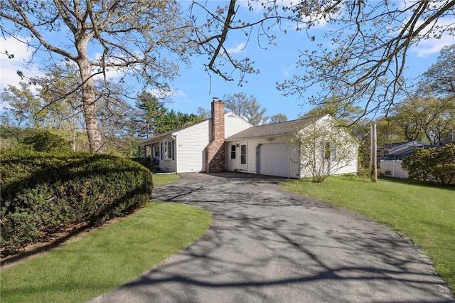 view of side of property with a garage, a yard, driveway, and a chimney