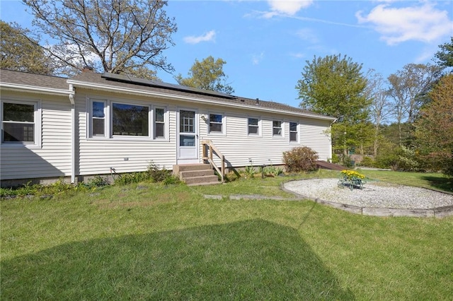 view of front facade with entry steps, solar panels, and a front yard