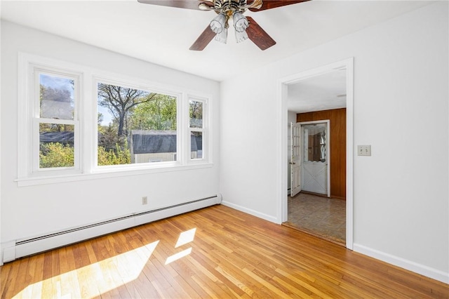 spare room featuring baseboards, ceiling fan, baseboard heating, and light wood-style floors