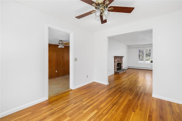 unfurnished living room featuring light wood-style floors, baseboards, ceiling fan, and baseboard heating