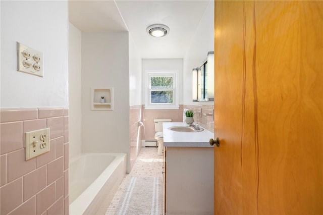bathroom with a washtub, tile walls, vanity, a baseboard heating unit, and toilet