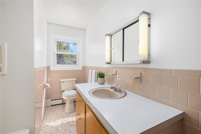 bathroom featuring wainscoting, baseboard heating, vanity, toilet, and tile walls