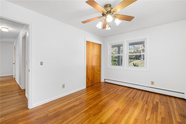 unfurnished room featuring baseboards, light wood-type flooring, ceiling fan, and a baseboard radiator