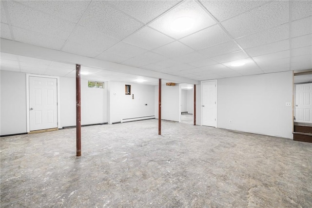 finished below grade area featuring a drop ceiling and a baseboard heating unit
