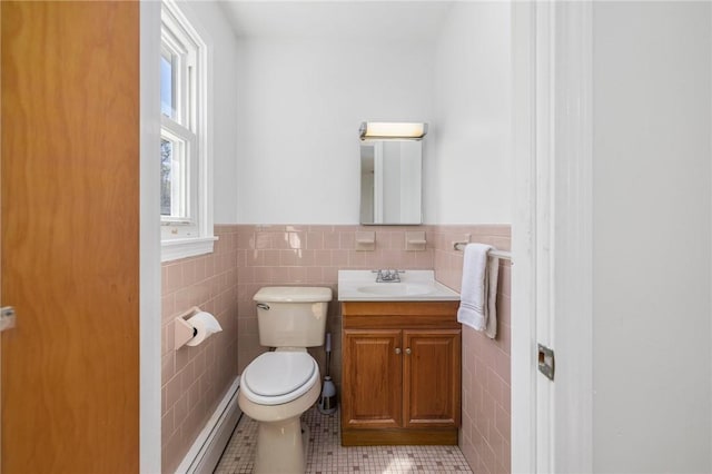 half bathroom featuring toilet, tile walls, a wainscoted wall, tile patterned floors, and a baseboard radiator
