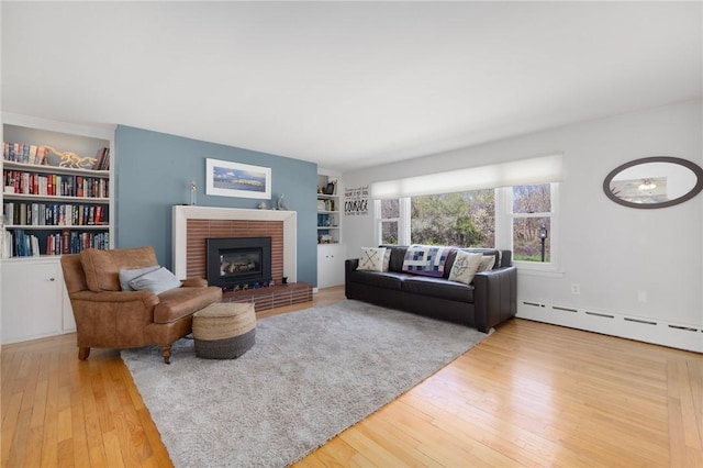 289 Oliphant Ln, Middletown, RI 02842 - living area with built in shelves, a fireplace, a baseboard heating unit, and wood finished floors
